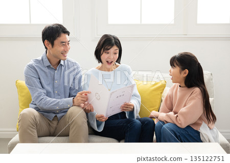 Elementary school girl showing her report card to her parents Elementary school girl showing her report card to her parents 135122751
