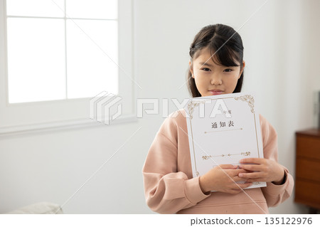 一名小學生拿著成績單，看起來很焦慮。 135122976