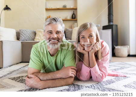 Smiling senior pair relaxing on floor Smiling senior pair relaxing on floor 135123215