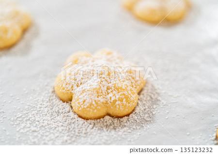 Freshly baked lemon spritz cookies are arranged on a sheet of parchment paper, each delicately dusted with powdered sugar. These buttery cookies have a crisp edge and a soft, melt-in-your-mouth Freshly baked lemon spritz cookies are arranged on a sheet of parchment paper, each delicately dusted with powdered sugar. These buttery cookies have a crisp edge and a soft, melt-in-your-mouth 135123232