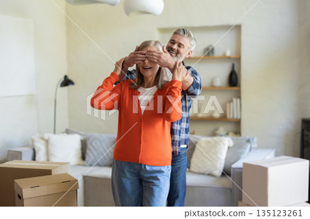 Senior couple sharing joyful moment with man surprising wife indoors Senior couple sharing joyful moment with man surprising wife indoors 135123261