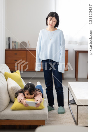 一位母親焦急地看著正全神貫注於智慧型手機的女兒。 135123427