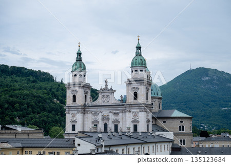 Salzburg Cathedral with twin baroque towers overlooking historic old town and green alpine hills Salzburg Cathedral with twin baroque towers overlooking historic old town and green alpine hills 135123684