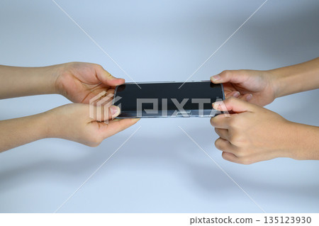 Children's hands holding a smartphone 135123930