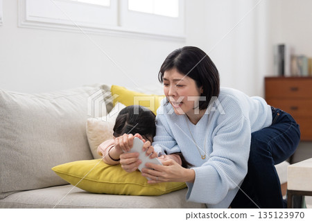 一位母親試圖沒收她上小學的女兒的智慧型手機。 一位母親試圖沒收她上小學的女兒的智慧型手機。 135123970
