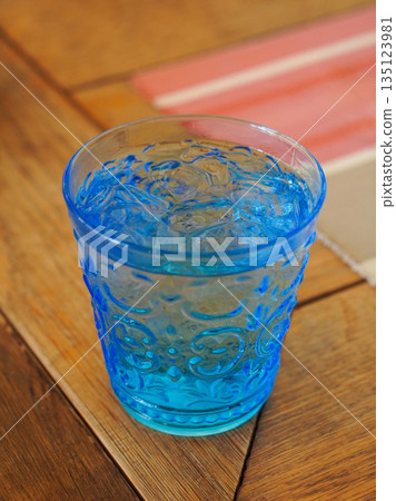 closeup Cold water is in a blue glass, placed on a wooden table background, fresh, cool, ice, Clear, clean, beneficial, copy space 135123981