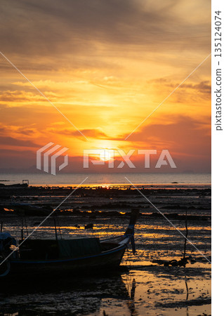 The sunrise above the horizontal line of the sea with the silhouette of fisherman boat in foreground 135124074
