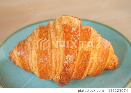 French pastry croissants on a plate on wooden table. Buttered croissant, breakfast. French pastry croissants on a plate on wooden table. Buttered croissant, breakfast. 135125074