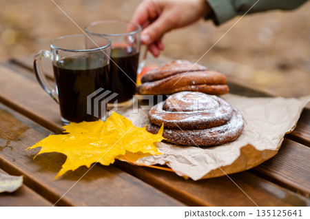 A hand reaches for a cup of coffee A hand reaches for a cup of coffee 135125641