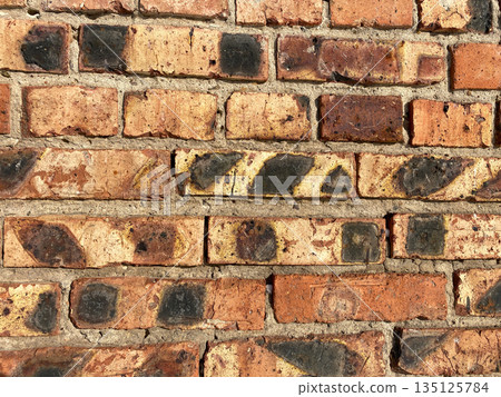 brick wall with an array of bricks in various shades of red and brown 135125784