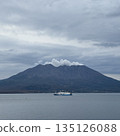 Smoke rising from Sakurajima and a ferry crossing the quiet Kinko Bay 135126088