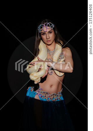 Woman performs dance with a snake in a dark setting during a cultural event in the evening Woman performs dance with a snake in a dark setting during a cultural event in the evening 135126408