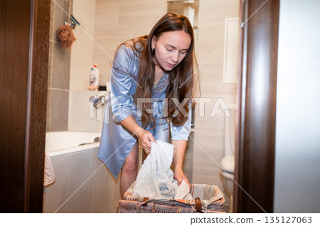 Happy housewife preparing to do laundry at home Happy housewife preparing to do laundry at home 135127063