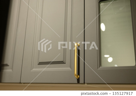 Gray kitchen cabinet with gold handle and glass panel Gray kitchen cabinet with gold handle and glass panel 135127917