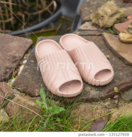 Beige slip-on sandals on stone path in outdoor garden setting 135127939