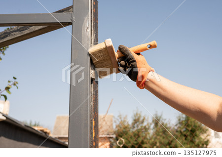 Hand painting metal frame outdoors with brush and gloves on sunny day Hand painting metal frame outdoors with brush and gloves on sunny day 135127975