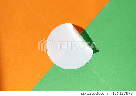 Circular white sticker on orange and green background with light shadow Circular white sticker on orange and green background with light shadow 135127978