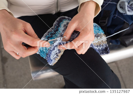 Adult female crocheting blue and grey yarn in close-up shot Adult female crocheting blue and grey yarn in close-up shot 135127987