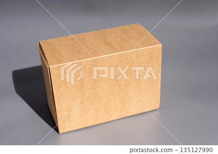 Plain cardboard box on gray background in minimalist setting. International Box Day Plain cardboard box on gray background in minimalist setting. International Box Day 135127990