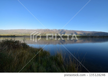 Lake Tekapo and mountains in New Zealand. A panoramic photo of the beautiful natural scenery with a mirror-like water surface. Lake Tekapo and mountains in New Zealand. A panoramic photo of the beautiful natural scenery with a mirror-like water surface. 135128246