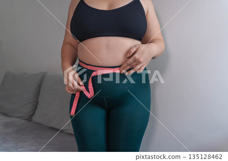 Fat women has overweight and she measuring abdomen girth with measure tape 135128462