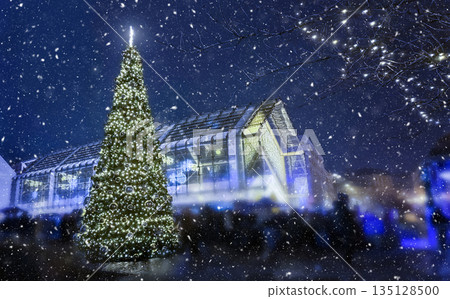 Christmas tree with festive lights in snowy winter night city scene 135128500