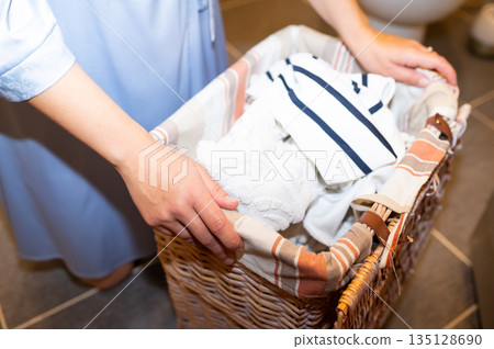 Woman's hands holding wicker basket with dirty laundry 135128690