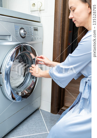 Beautiful housewife closing washing machine, preparing to do laundry at home Beautiful housewife closing washing machine, preparing to do laundry at home 135128705
