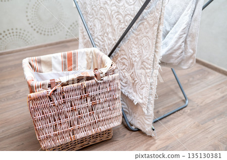 Drying rack with hanging laundry and laundry basket nearby at home Drying rack with hanging laundry and laundry basket nearby at home 135130381