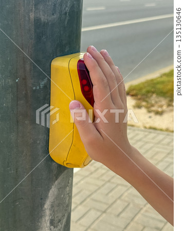Child hand pressing pedestrian crossing button at crosswalk Child hand pressing pedestrian crossing button at crosswalk 135130646