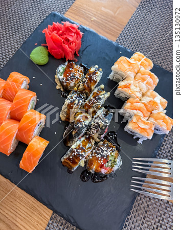 Sushi roll set served on a stone plate with wasabi and pickled ginger, Japanese cuisine presentation Sushi roll set served on a stone plate with wasabi and pickled ginger, Japanese cuisine presentation 135130972
