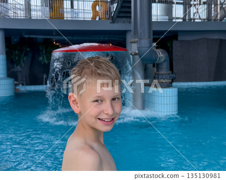 Happy teenage boy enjoying swimming pool fun at a water park on a sunny day 135130981