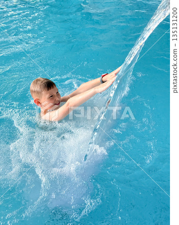 Happy teenage boy enjoying swimming pool fun at a water park on a sunny day 135131200