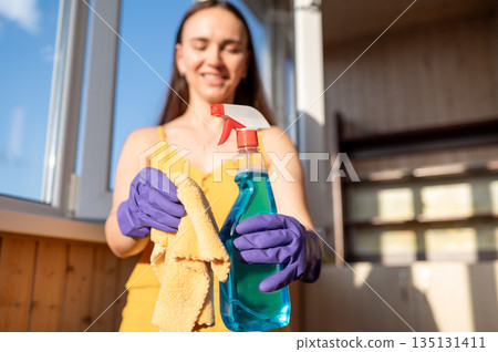 Young beautiful housewife in gloves holding window cleaner and cloth, focus on hands Young beautiful housewife in gloves holding window cleaner and cloth, focus on hands 135131411