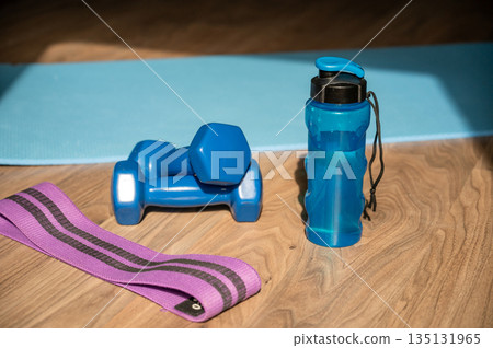 Dumbbells resistance band and water bottle on yoga mat at home Dumbbells resistance band and water bottle on yoga mat at home 135131965
