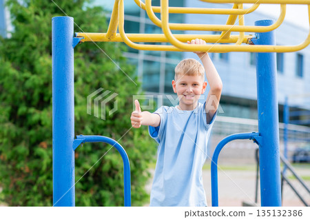 Smiling boy showing thumbs up at outdoor playground 135132386