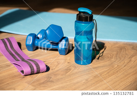 Dumbbells resistance band and water bottle on yoga mat at home Dumbbells resistance band and water bottle on yoga mat at home 135132781