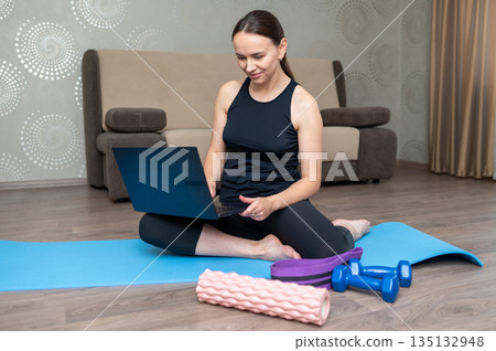 Young woman home exercise with dumbbells, yoga mat, foam roller and resistance band Young woman home exercise with dumbbells, yoga mat, foam roller and resistance band 135132948