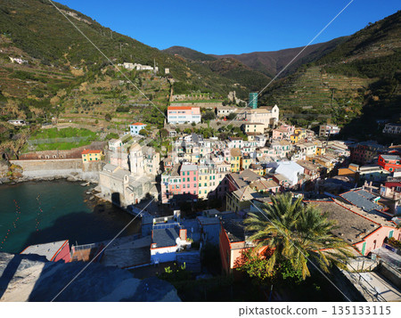 View of Vernazza, town in Cinque Terre, from mountain. Nature and sea, traditional buildings of Liguria, Italy. Architecture protected by UNESCO. Background for design. View of Vernazza, town in Cinque Terre, from mountain. Nature and sea, traditional buildings of Liguria, Italy. Architecture protected by UNESCO. Background for design. 135133115