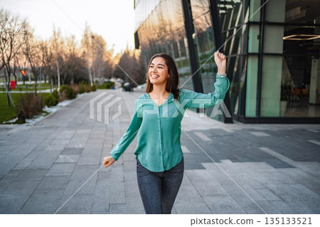 Young businesswoman celebrating success while walking near office building 135133521