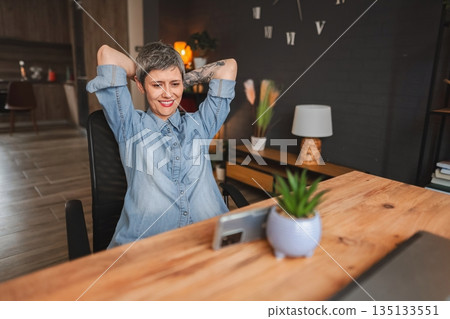 Freelancer relaxing after finishing work on a laptop at home office Freelancer relaxing after finishing work on a laptop at home office 135133551