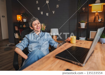 Freelancer laughing while working from home office 135133554