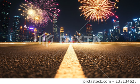 Colorful fireworks exploding over illuminated modern city skyline at night with empty asphalt road in the foreground, celebrating new year's eve or other special event 135134623