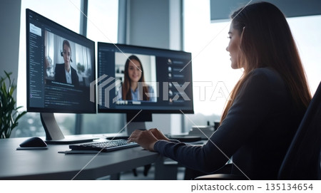 Confident businesswoman having a video conference with her colleagues on a desktop computer, working from a modern office with a window view 135134654