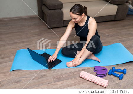 Young woman doing home workout with dumbbells, yoga mat, foam roller and resistance band Young woman doing home workout with dumbbells, yoga mat, foam roller and resistance band 135135132