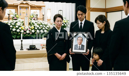 在殯儀館，三代同堂的哀悼者們神情悲痛，他們的兒子手捧著逝者的畫像。 135135649