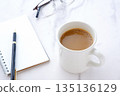 An image of working at a desk with a ring-type notepad and pen while drinking coffee. 135136129