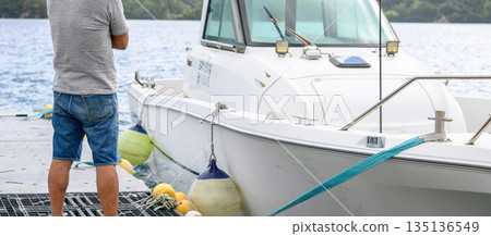 一名男子站在碼頭上，旁邊是一艘船（照片由沖繩海濱度假村雅提供） 135136549