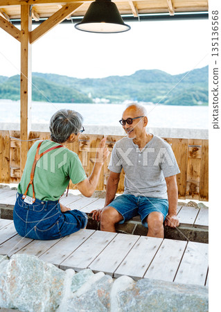 An elderly couple having a conversation in a foot bath (Photo courtesy of Oki Seaside Resort Miyabi) 135136568