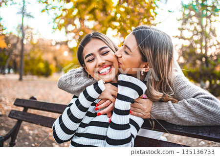 Two Women Kissing and hugging on a Park Bench Two Women Kissing and hugging on a Park Bench 135136733